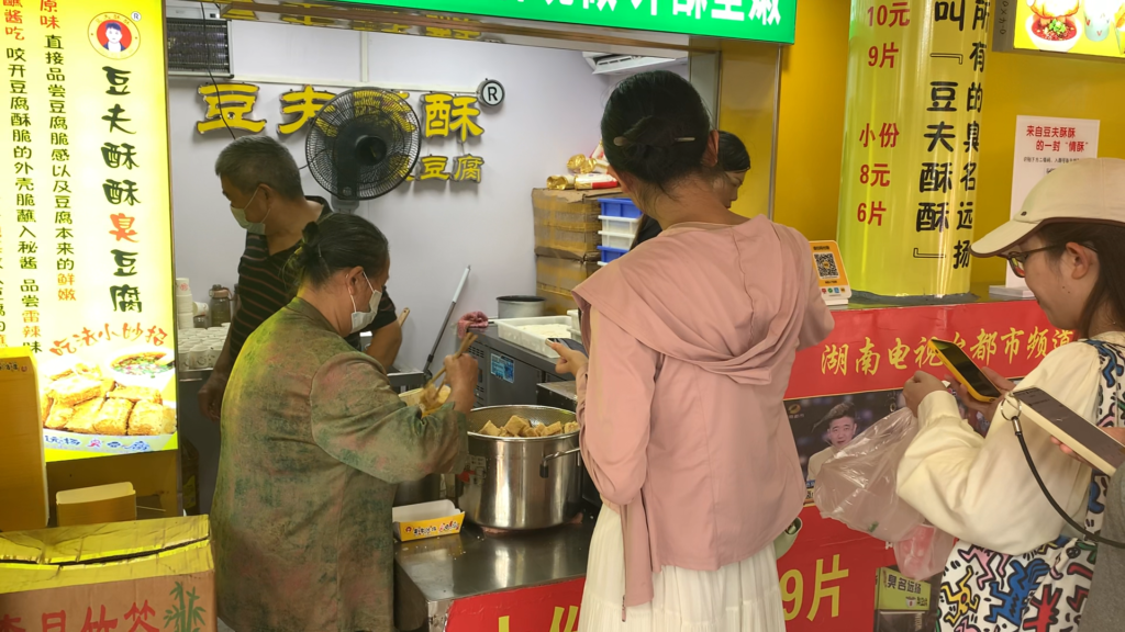 Price signs at a Chinese university snack street, showing stinky tofu and sugar-oil rice cakes