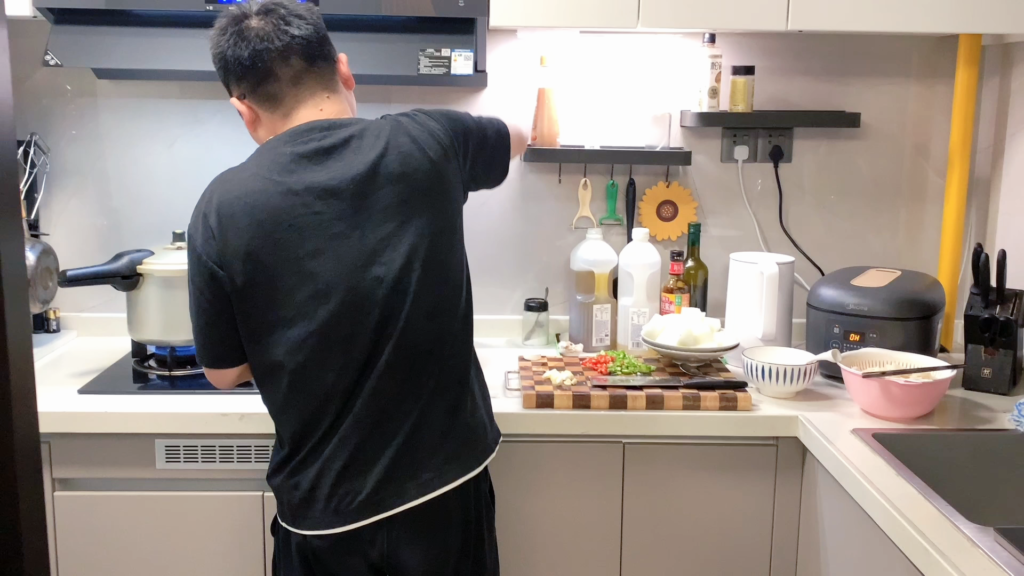 Husband cooking dinner at the stove in a home kitchen in Hunan, China
