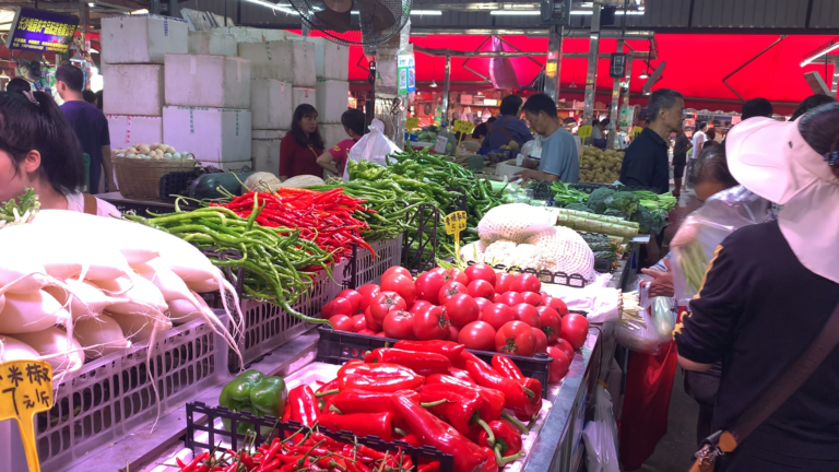 Vegetable stall at a Chinese wet market with fresh vegetables piled on the table
